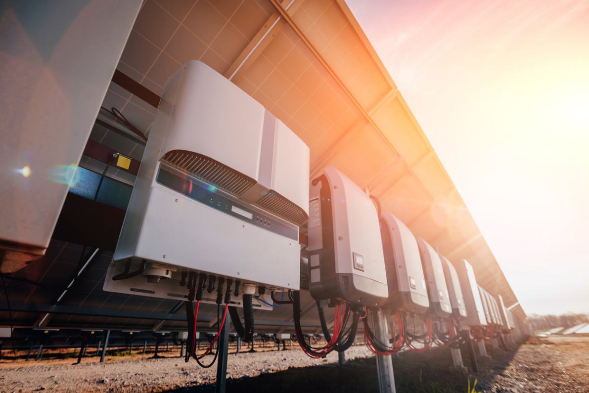 solar inverters are hanging on back of solar structure with sun rays in the background
